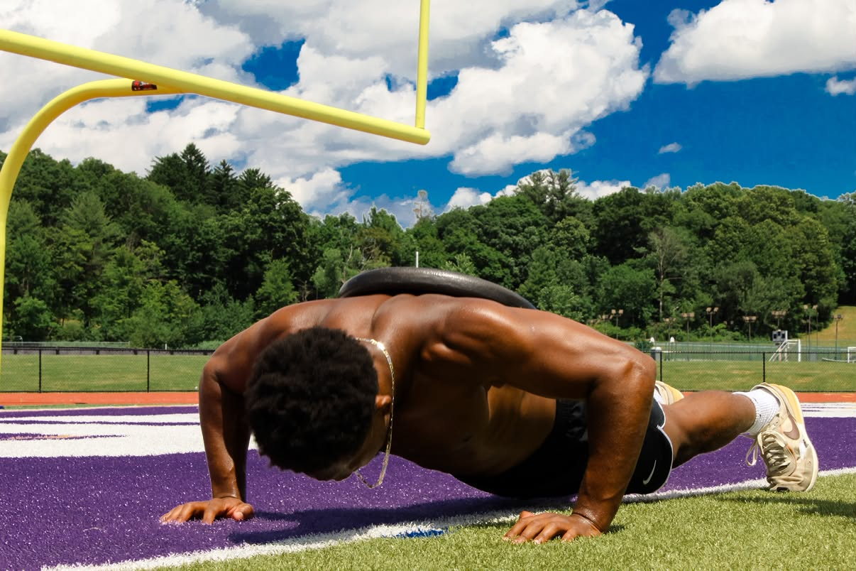 A TATO athlete working through a weighted push-up set on the field